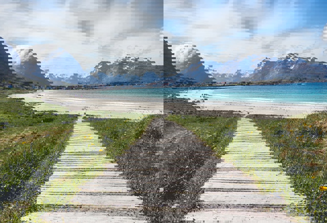 Path going down to a beach with mountains in the distance