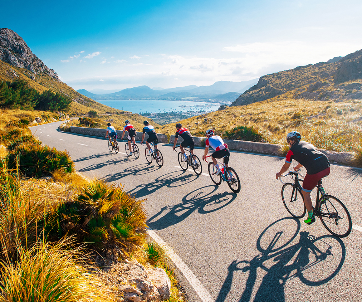 Six cyclists on a road reaching a beach