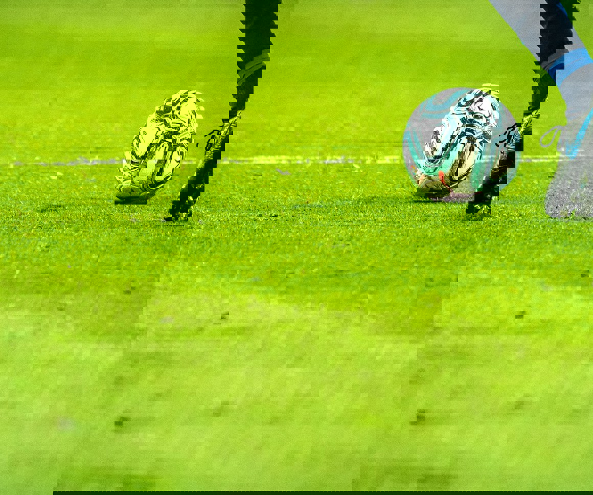 Footballer on a grassy pitch approaching a football