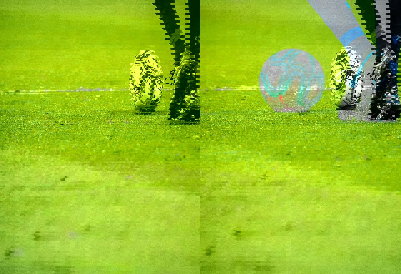 Footballer on a grassy pitch approaching a football