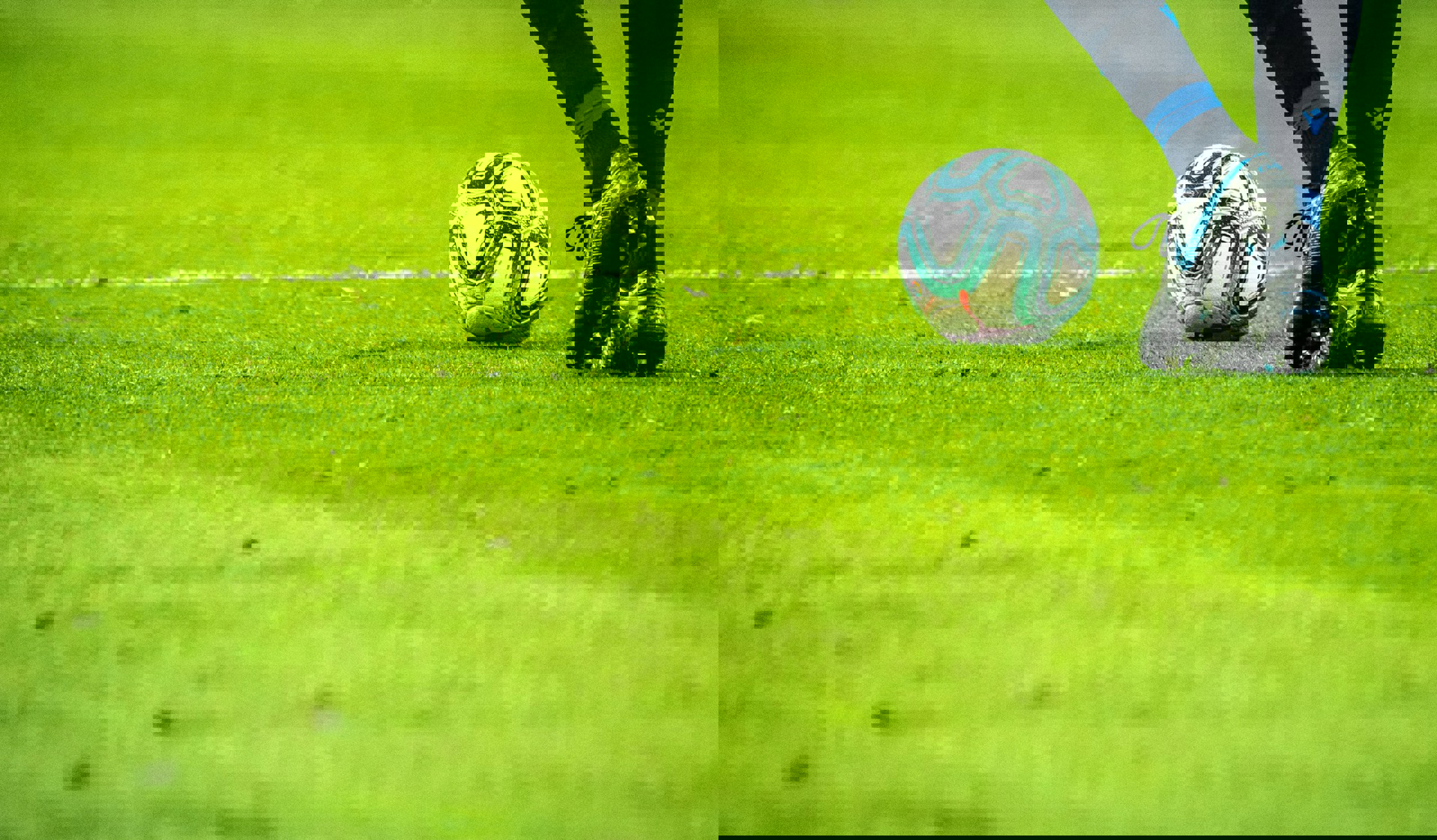 Footballer on a grassy pitch approaching a football