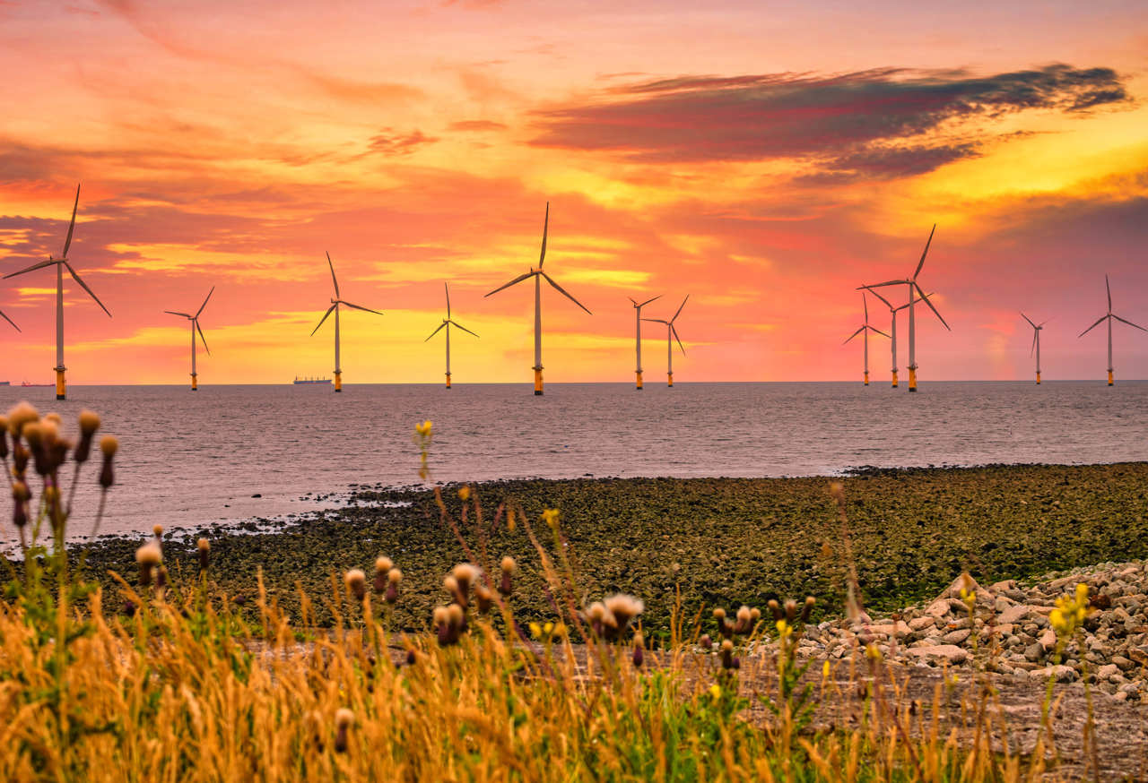 Offshore Wind Turbine in a Wind farm under construction off the England coast at sunset