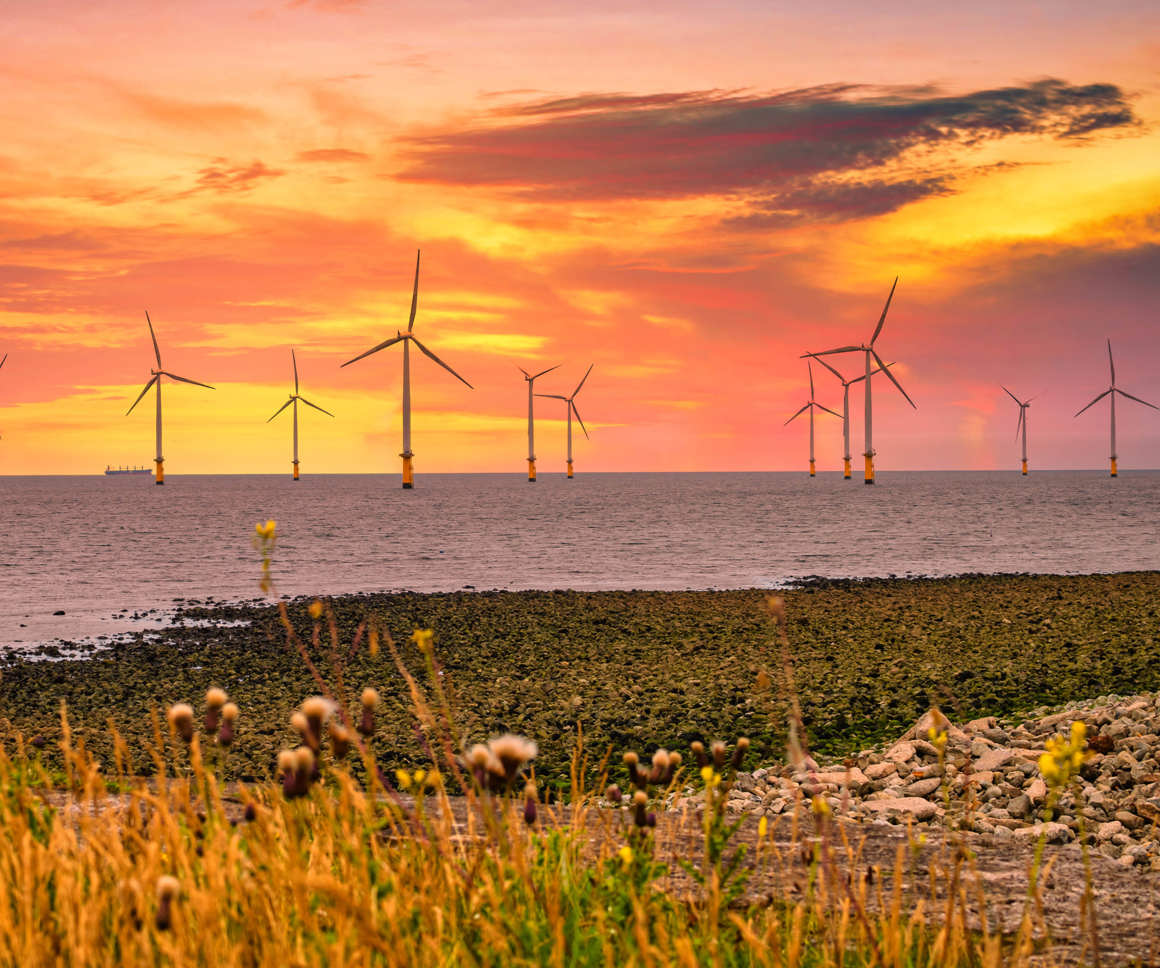 Offshore Wind Turbine in a Wind farm under construction off the England coast at sunset
