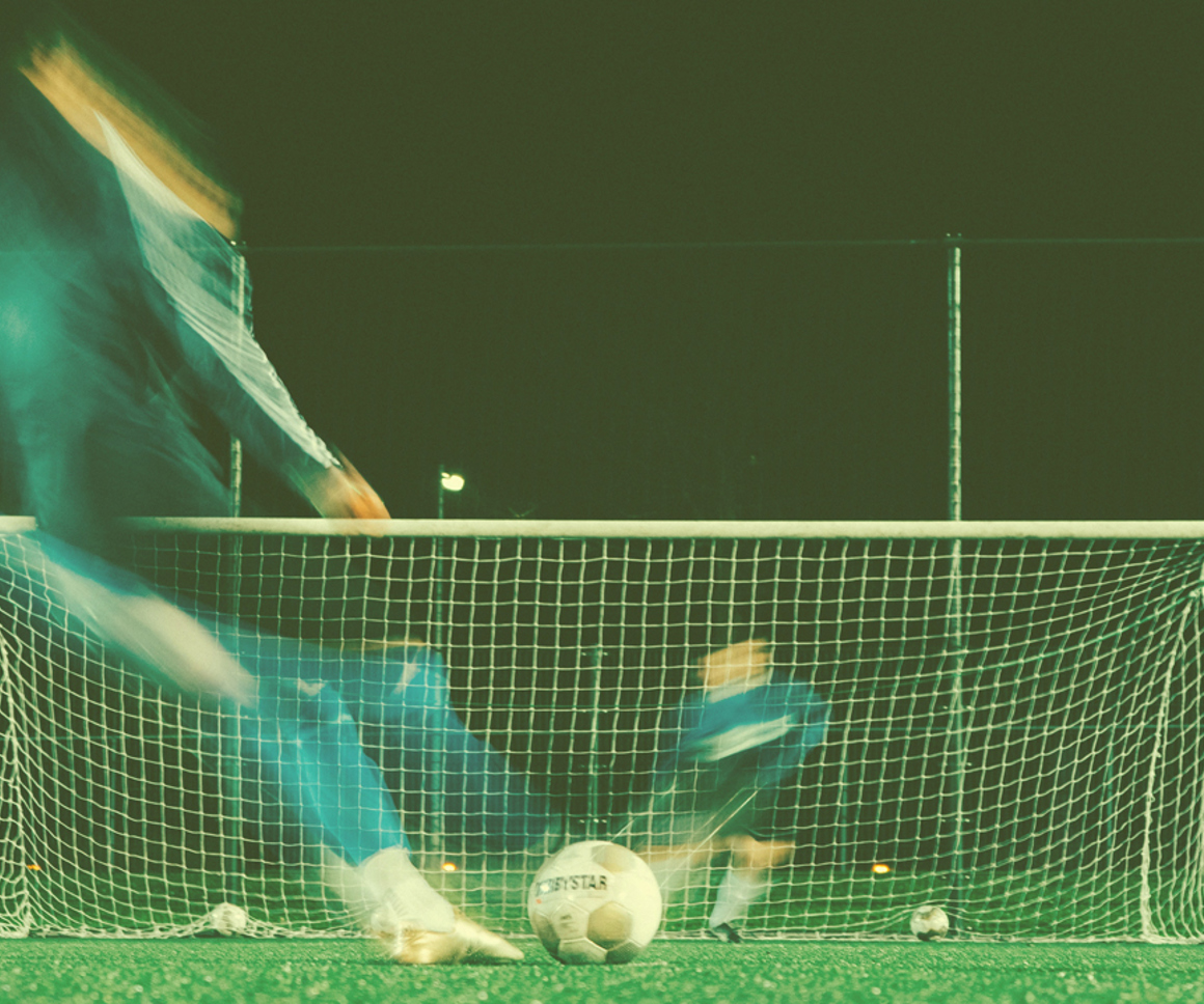 Footballer kicking a ball into a goal