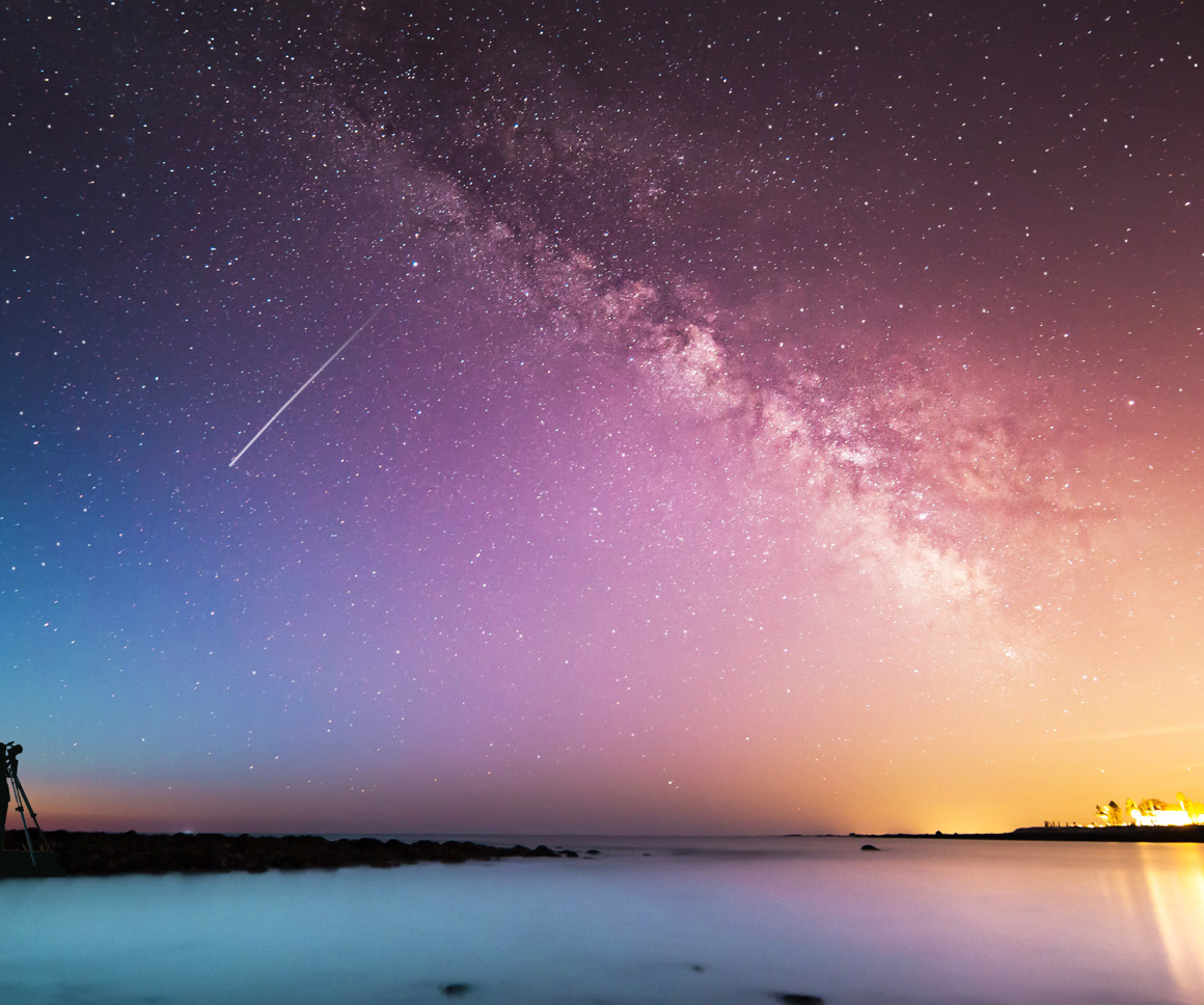 Person looking through telescope at galaxy