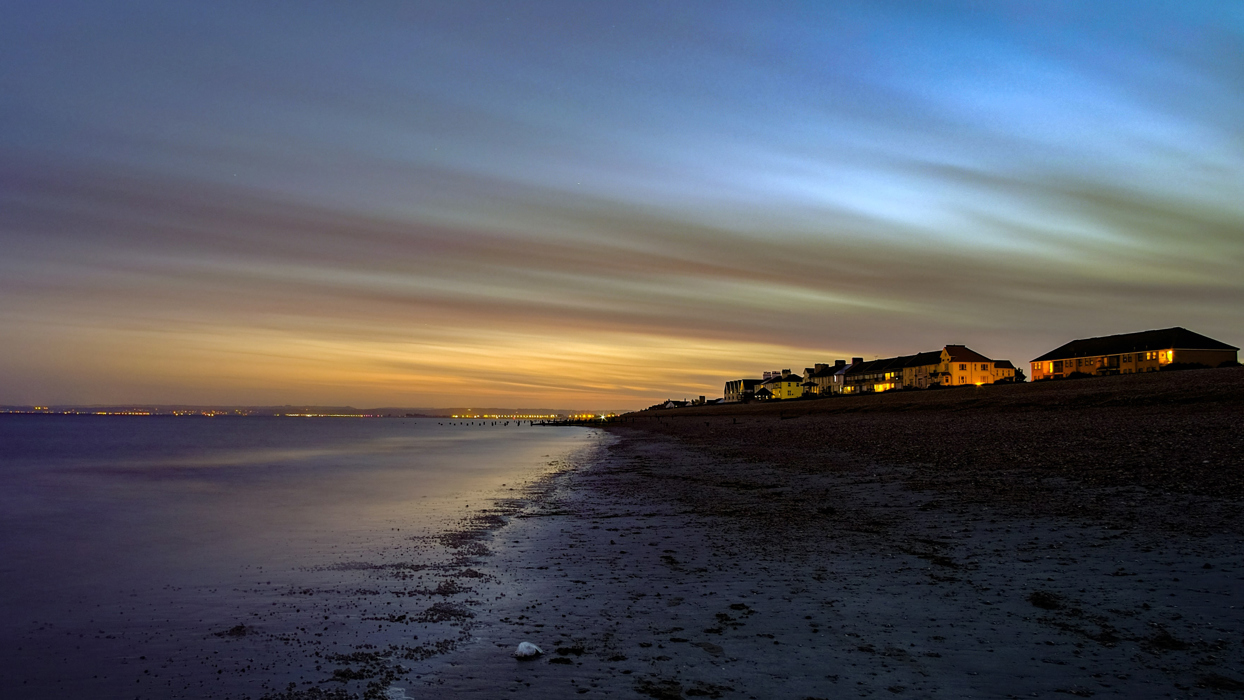 Houses looking out over a beach at sunset