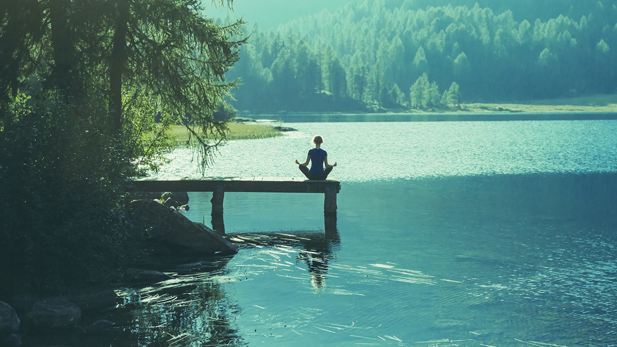 Woman meditating near a lake