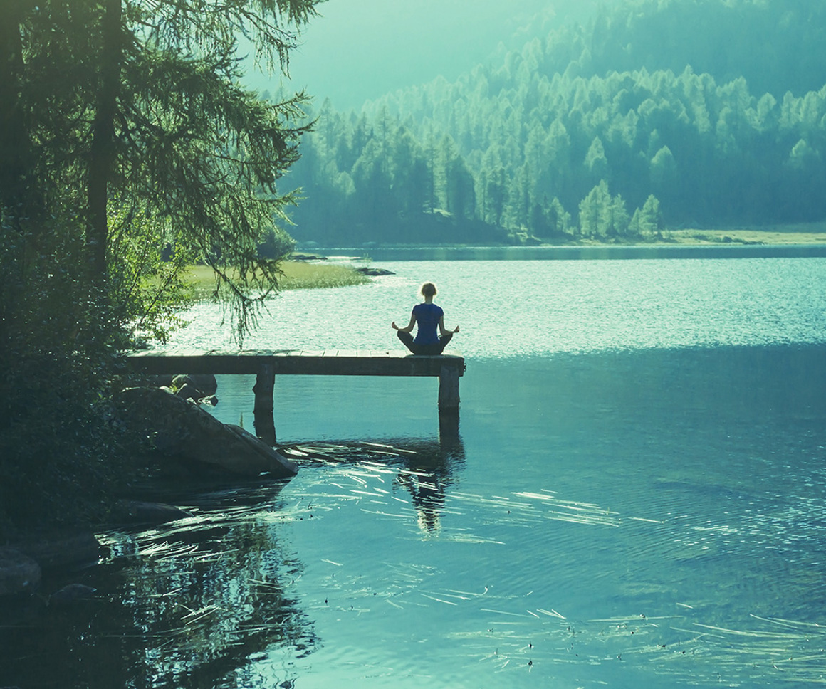 Woman meditating near a lake