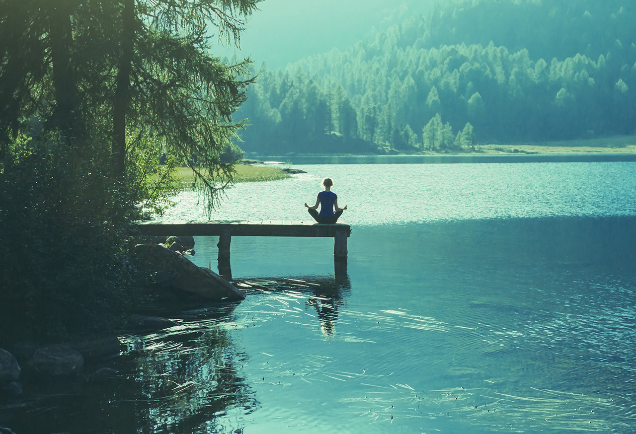 Woman meditating near a lake