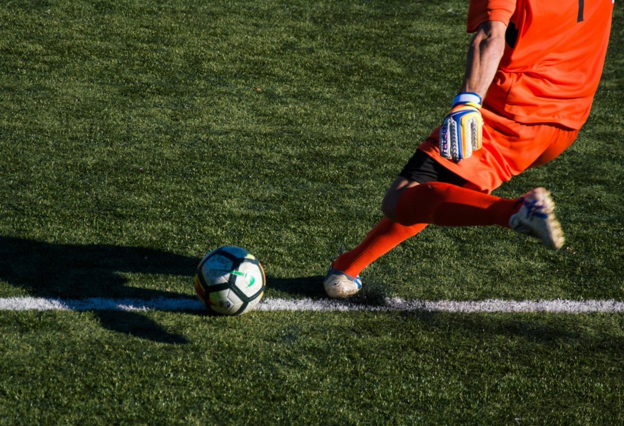 Football in red kit kicking a football