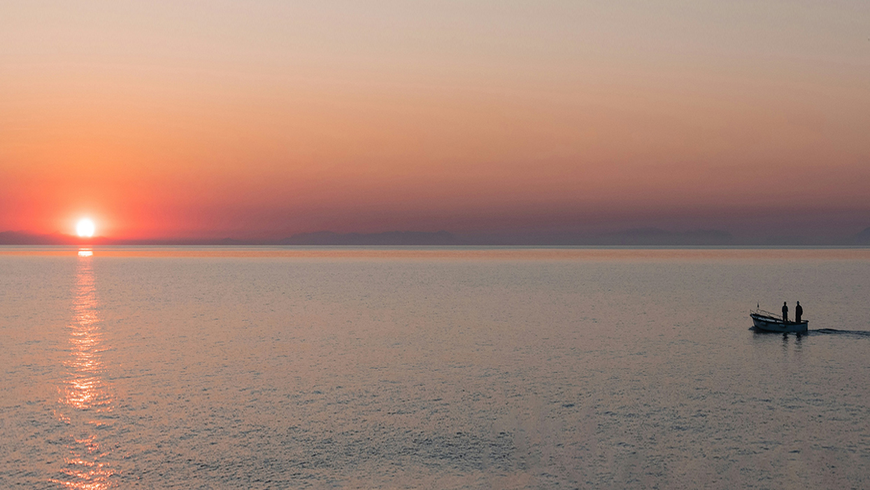 Small boat on water as the sun sets