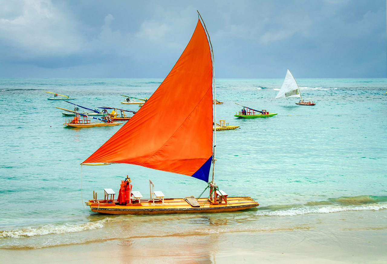 Raft with a large orange sail on a beach