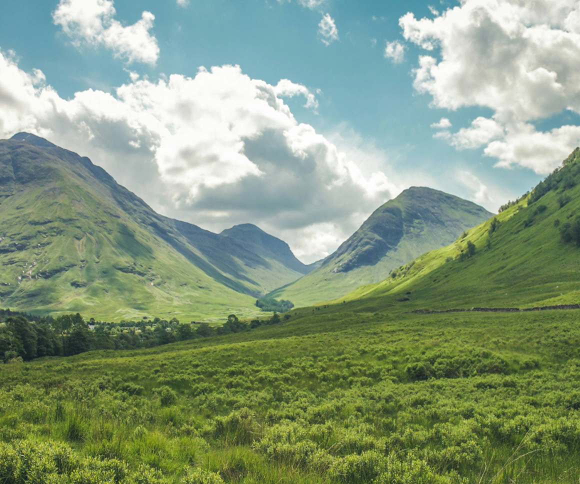 A green valley with clouds in the sky