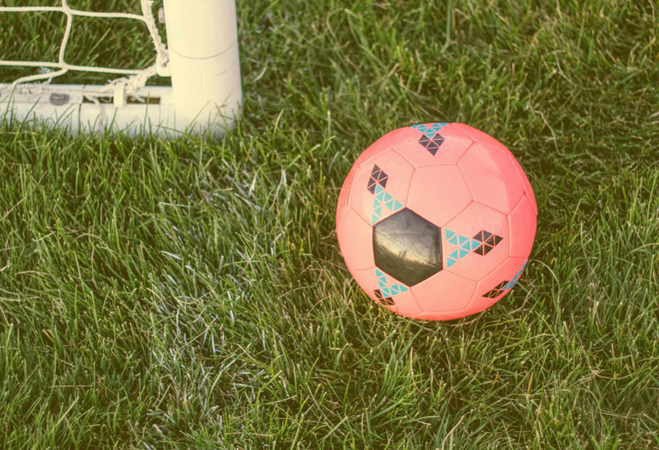 Football on a pitch next to a goal post